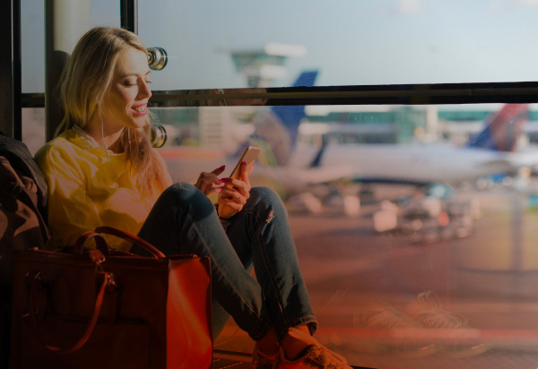 Immagine che rappresenta una ragazza seduta in aereoporto che guarda il cellulare