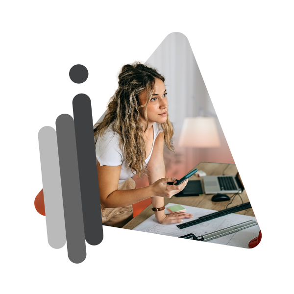 ragazza appoggiata sulla scrivania che guarda il monitor del pc con il cellulare in mano